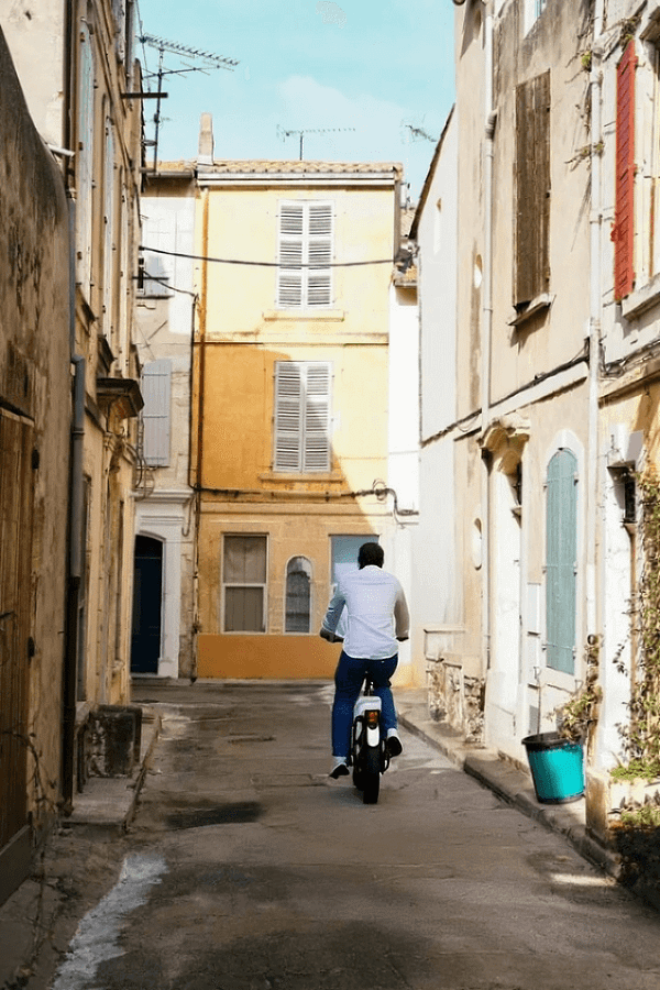 Une ruelle provençale à vélo Rue étroite bordée de façades anciennes, un cycliste déambulant dans un village de Provence